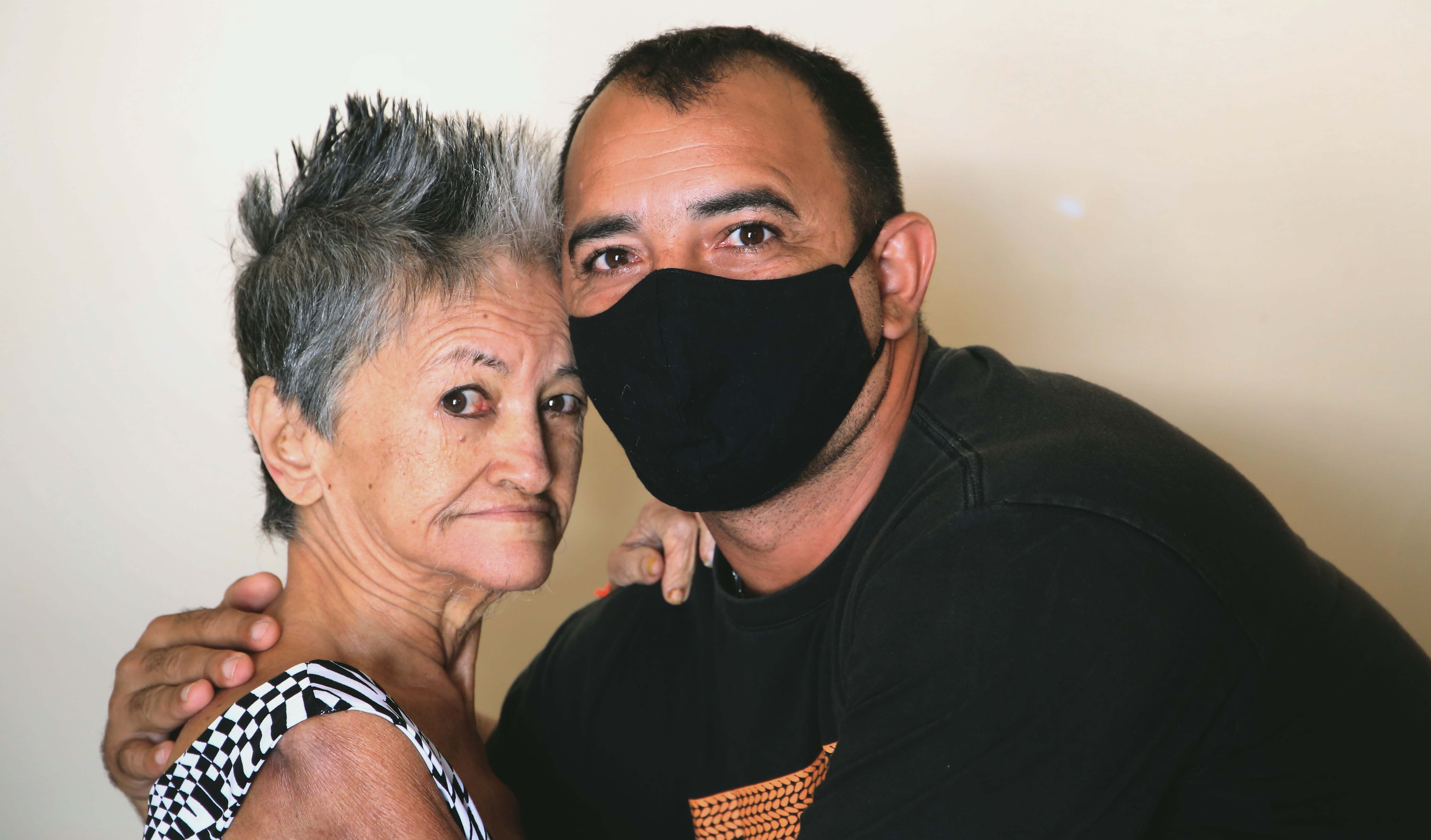 homem de máscara abraçando senhora idosa. ambos posam para a foto